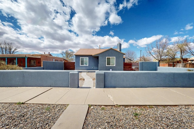 view of front of home featuring a fenced front yard, stucco siding, metal roof, and a gate