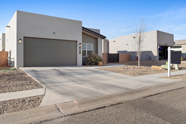 view of front of house featuring stucco siding, a gate, fence, concrete driveway, and an attached garage