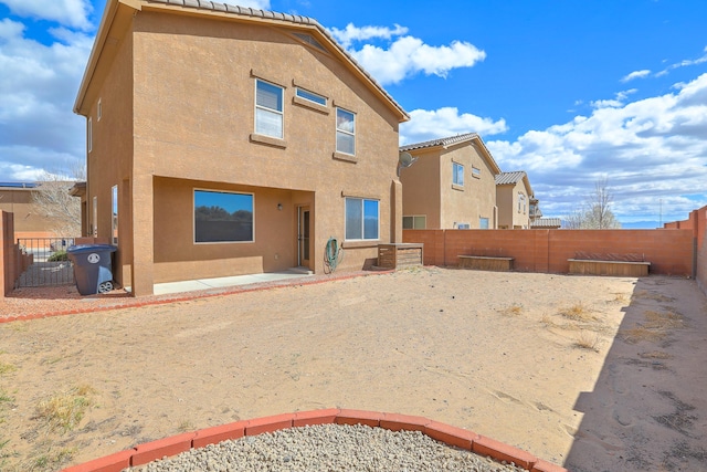 rear view of house with stucco siding and a fenced backyard