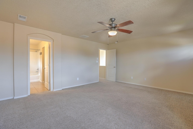 unfurnished bedroom with light carpet, visible vents, a textured ceiling, and ensuite bath