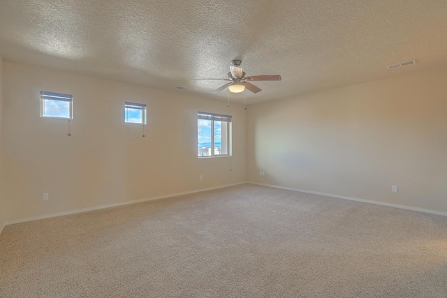 empty room featuring visible vents, a textured ceiling, baseboards, light colored carpet, and ceiling fan