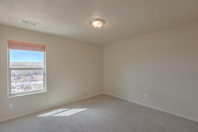 unfurnished room featuring baseboards, visible vents, a textured ceiling, and carpet