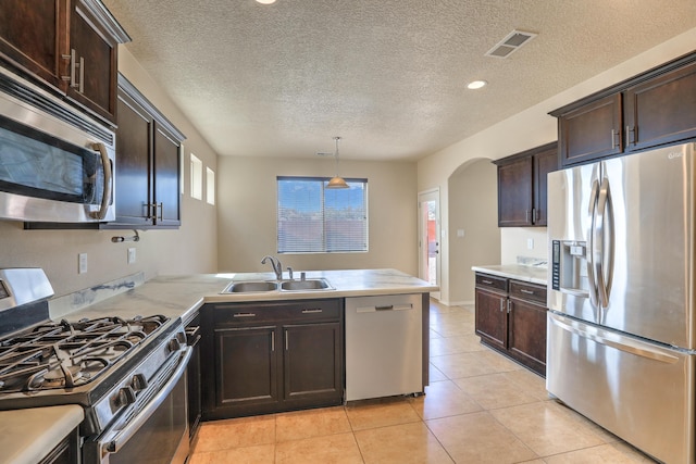 kitchen with visible vents, a peninsula, light tile patterned flooring, stainless steel appliances, and a sink