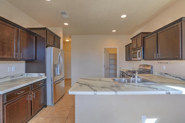 kitchen featuring visible vents, dark brown cabinets, a peninsula, light tile patterned flooring, and stainless steel appliances