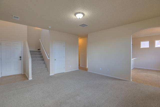 spare room with visible vents, stairway, light colored carpet, and arched walkways