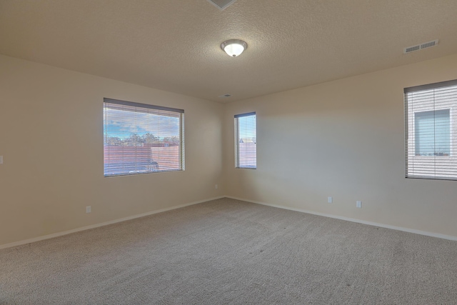 carpeted empty room featuring visible vents, a textured ceiling, and baseboards