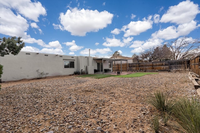 rear view of house featuring stucco siding, a patio, and a fenced backyard