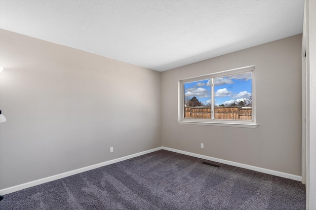 unfurnished room featuring visible vents, baseboards, and dark colored carpet