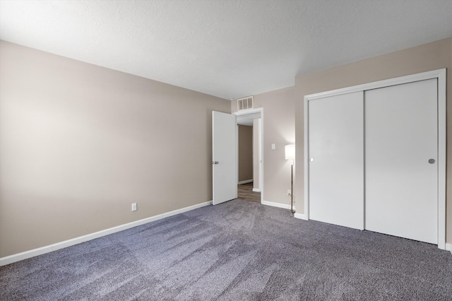 unfurnished bedroom with visible vents, a textured ceiling, a closet, carpet floors, and baseboards