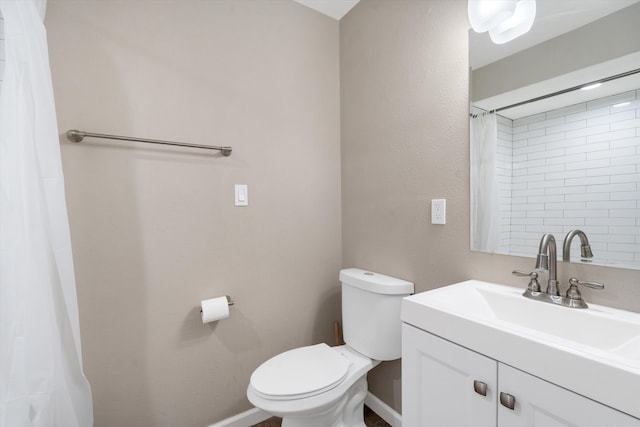 full bath featuring toilet, vanity, and baseboards