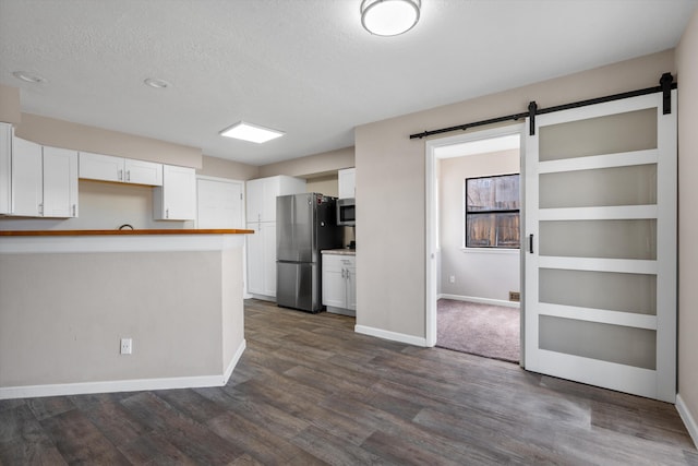 kitchen featuring dark wood finished floors, white cabinets, appliances with stainless steel finishes, a textured ceiling, and a barn door