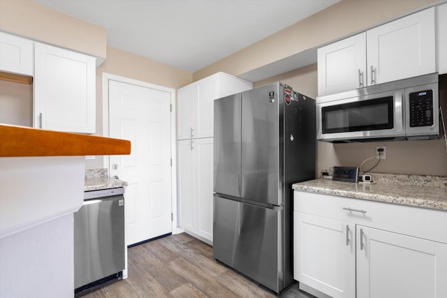 kitchen featuring white cabinets, stainless steel appliances, and light wood-type flooring