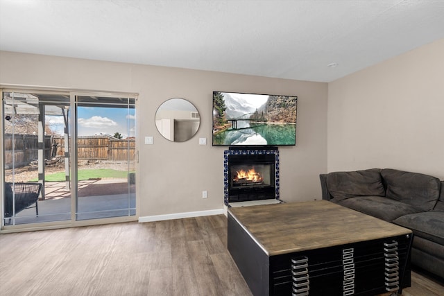 living area with wood finished floors, baseboards, and a tile fireplace