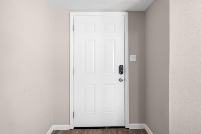 doorway to outside with wood finished floors and baseboards