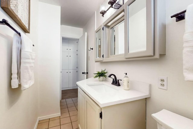 bathroom featuring vanity, toilet, baseboards, and tile patterned flooring