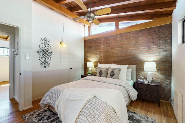 bedroom with brick wall, beamed ceiling, radiator heating unit, wooden ceiling, and wood finished floors