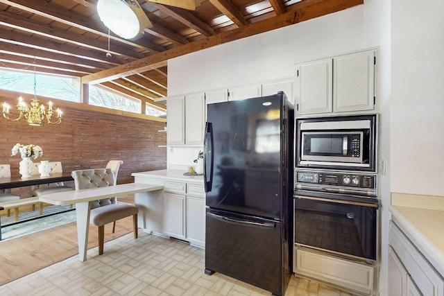 kitchen with black appliances, vaulted ceiling with beams, light countertops, an inviting chandelier, and white cabinetry