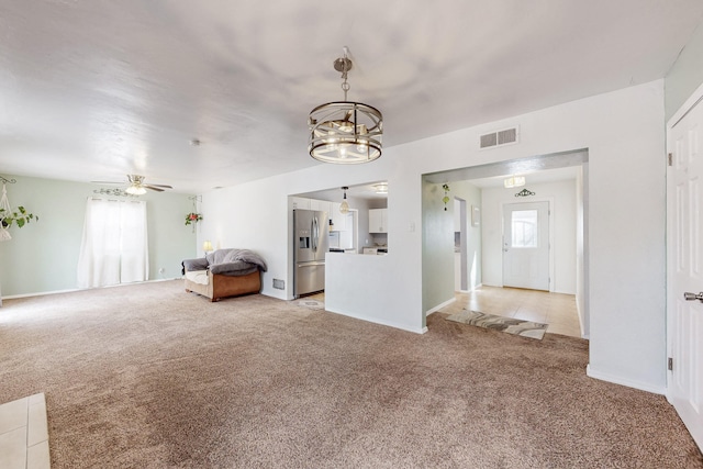 unfurnished living room with ceiling fan with notable chandelier, visible vents, and light carpet