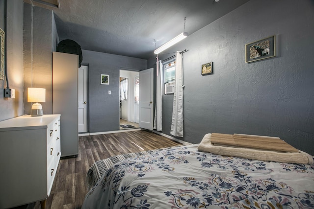 bedroom featuring a textured ceiling, dark wood finished floors, and a textured wall