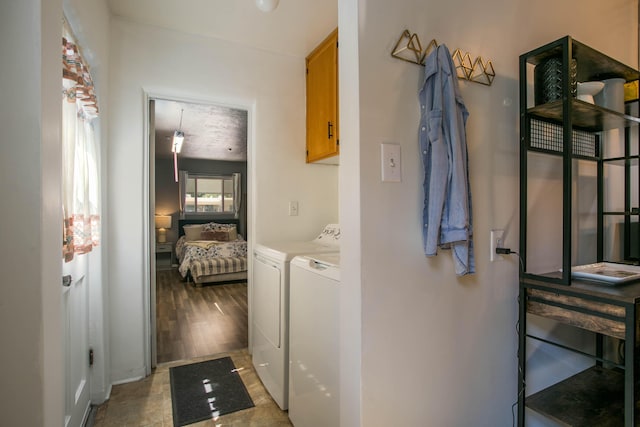 clothes washing area featuring washer and dryer, light wood-style flooring, and cabinet space