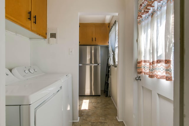 clothes washing area featuring washing machine and dryer, baseboards, and stone finish flooring