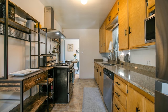 kitchen with dark stone counters, stainless steel appliances, wall chimney range hood, and a sink