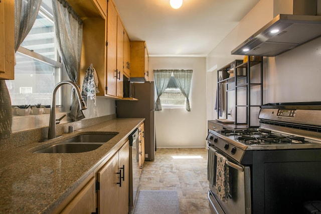 kitchen featuring appliances with stainless steel finishes, dark stone counters, wall chimney exhaust hood, and a sink