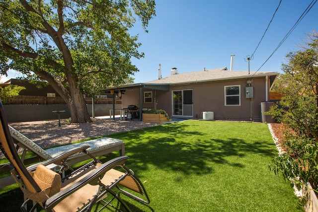 rear view of property featuring stucco siding, a lawn, a patio, and fence