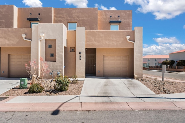 southwest-style home with a garage, driveway, and stucco siding