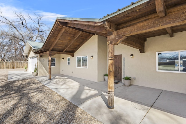 exterior space featuring a patio, fence, a garage, and stucco siding