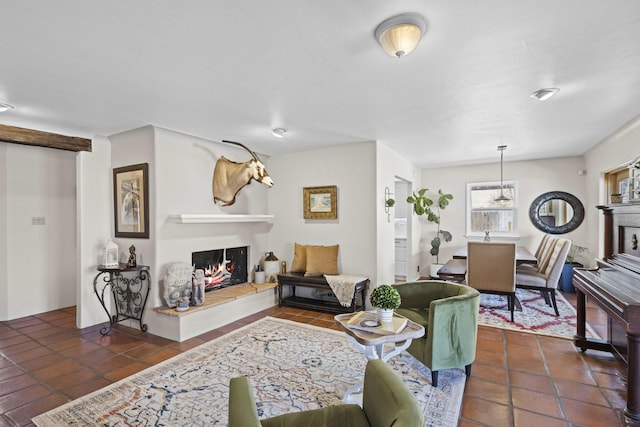 living room featuring dark tile patterned floors and a lit fireplace