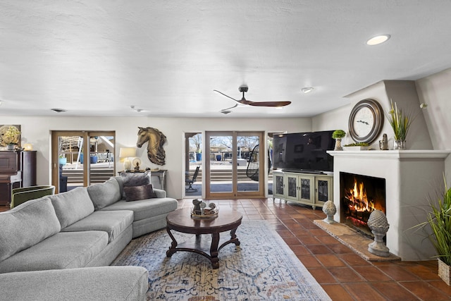 living room with recessed lighting, a lit fireplace, a ceiling fan, and dark tile patterned flooring