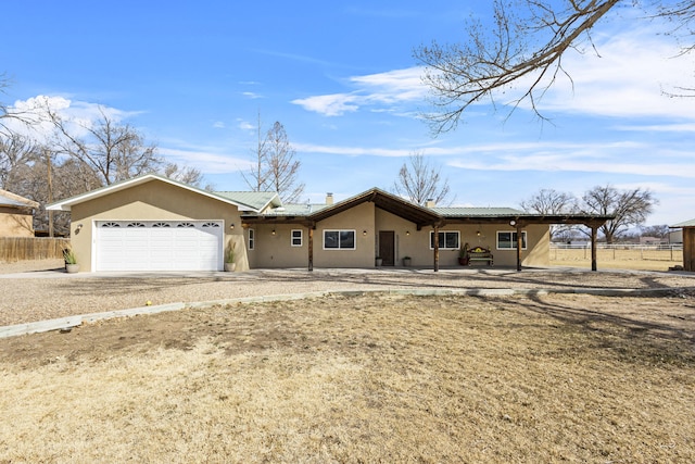 view of front of home with fence, an attached garage, stucco siding, dirt driveway, and a tiled roof