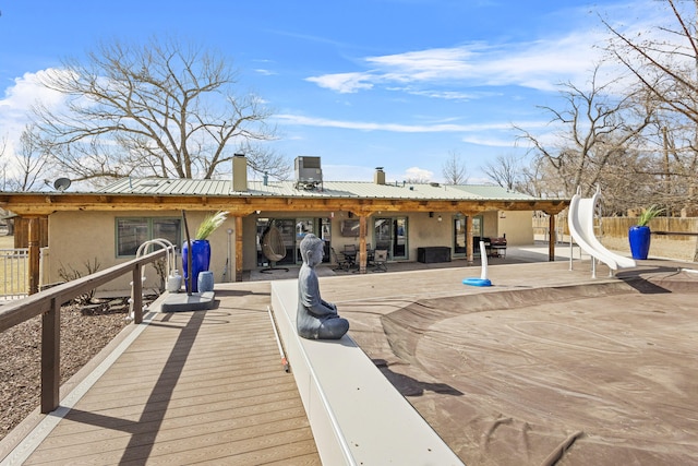 rear view of property featuring fence, stucco siding, a chimney, a patio area, and metal roof