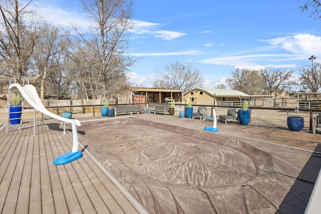 wooden terrace featuring an outdoor structure and fence