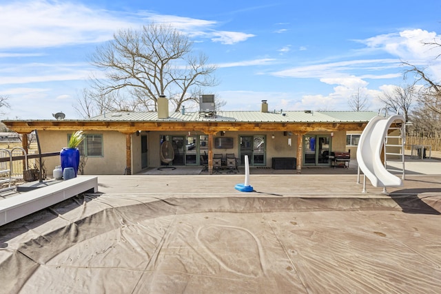 back of property featuring a patio area, stucco siding, a chimney, and metal roof