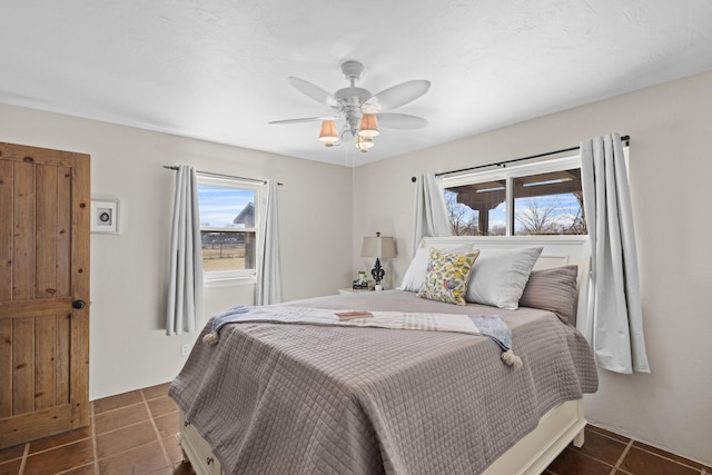 bedroom with dark tile patterned floors and ceiling fan