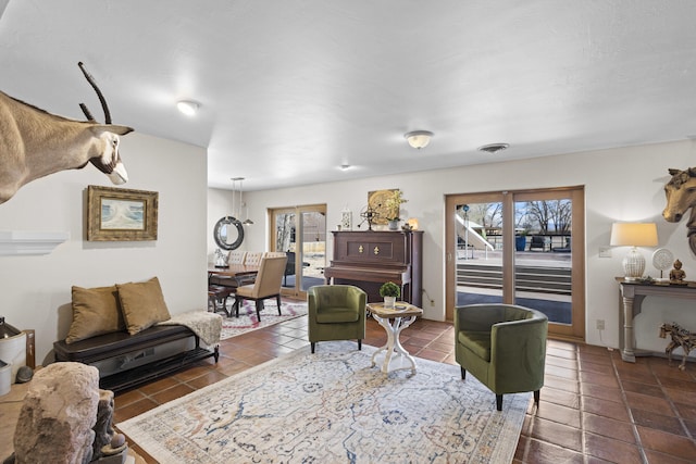 living area with dark tile patterned floors, plenty of natural light, and visible vents