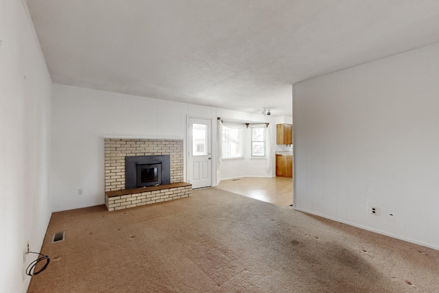 unfurnished living room featuring a fireplace, carpet, and visible vents