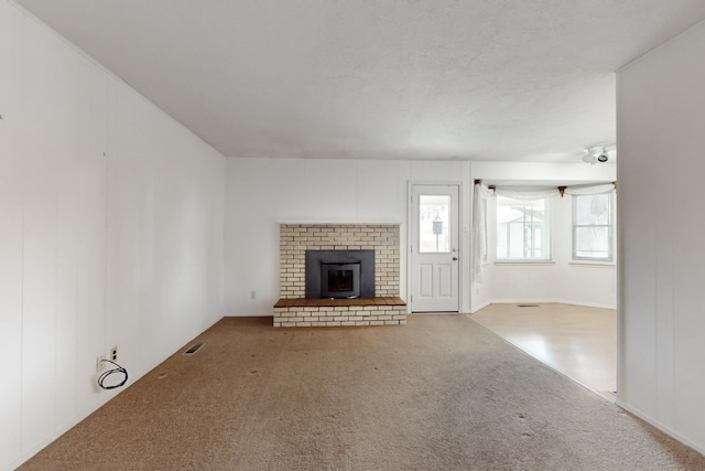 unfurnished living room with visible vents, carpet floors, and a fireplace