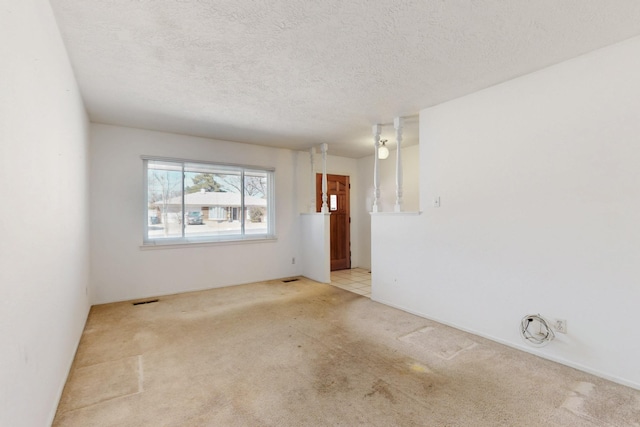 carpeted empty room with visible vents and a textured ceiling