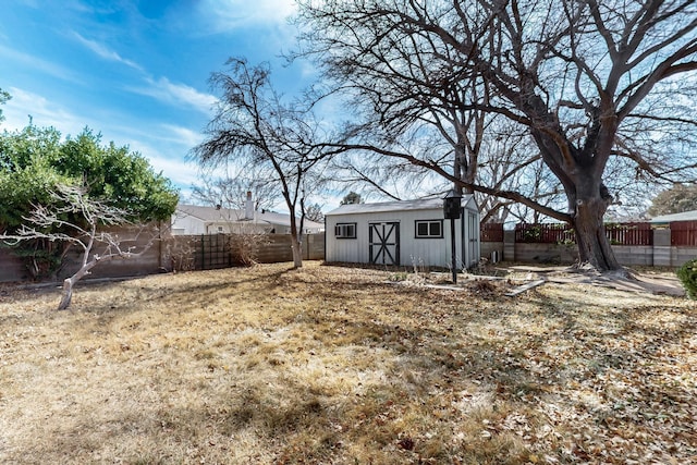 view of yard with a fenced backyard, a storage unit, and an outdoor structure