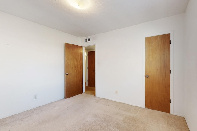 unfurnished room with visible vents, light carpet, and a textured ceiling