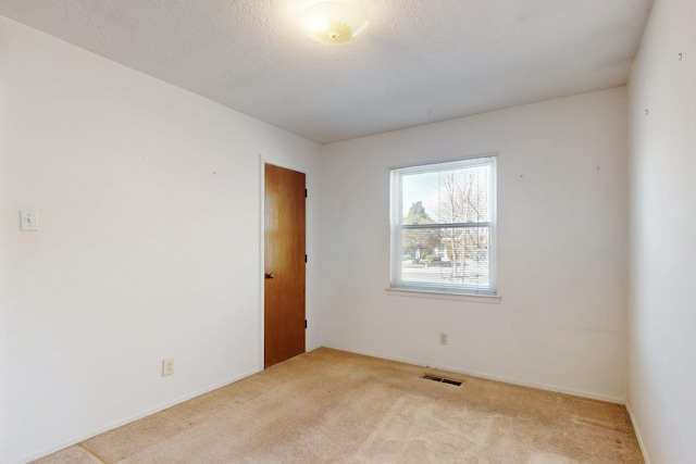 carpeted spare room featuring visible vents and a textured ceiling