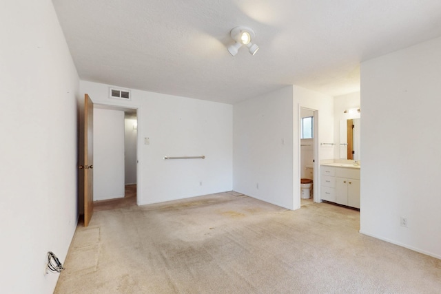 unfurnished bedroom with connected bathroom, visible vents, and light carpet