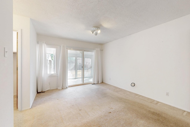 empty room with a textured ceiling and light carpet