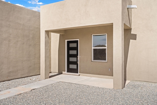 property entrance with a patio and stucco siding