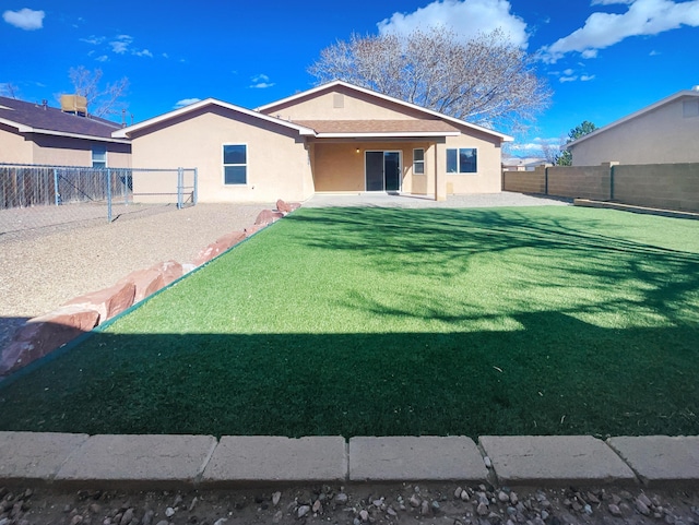 back of property featuring a yard, a fenced backyard, and stucco siding