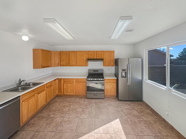 kitchen featuring light tile patterned flooring, a sink, stainless steel appliances, light countertops, and under cabinet range hood