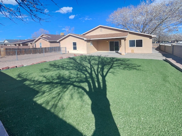 rear view of house with roof with shingles, stucco siding, a yard, a fenced backyard, and a patio area